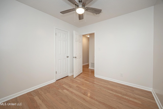 unfurnished room featuring visible vents, light wood-style flooring, ceiling fan, a textured ceiling, and baseboards