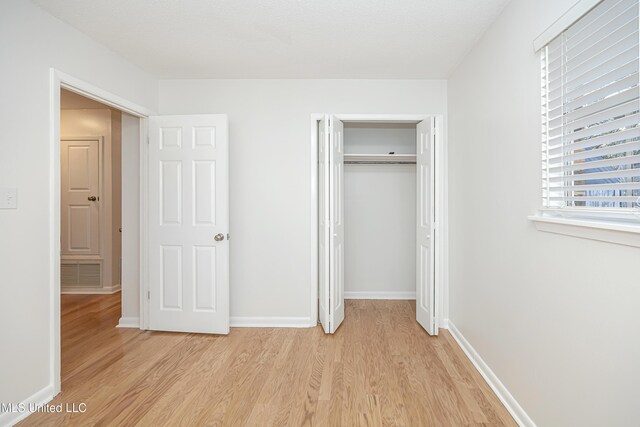 unfurnished bedroom with a closet, visible vents, light wood-style flooring, and baseboards