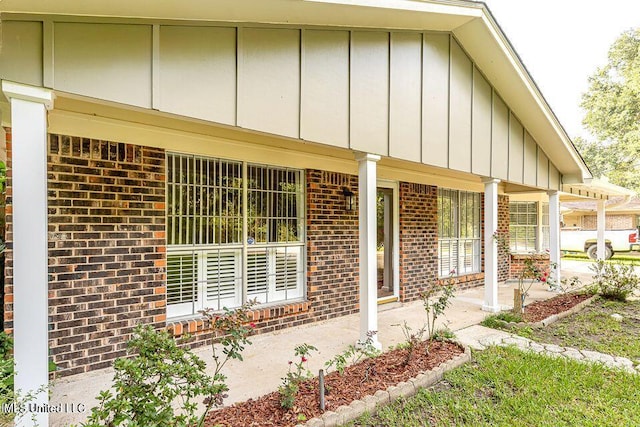 property entrance featuring board and batten siding, covered porch, and brick siding