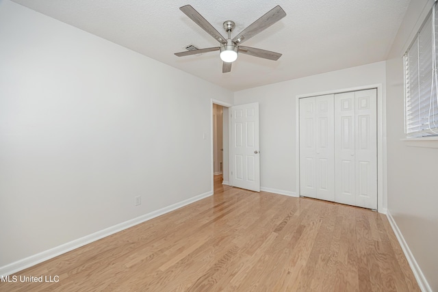 unfurnished bedroom featuring a closet, ceiling fan, a textured ceiling, light wood-type flooring, and baseboards