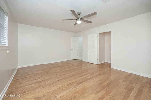 spare room with light wood-style flooring, baseboards, ceiling fan, and a textured ceiling