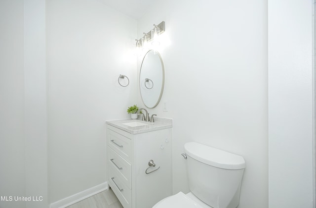 bathroom featuring vanity, toilet, and baseboards