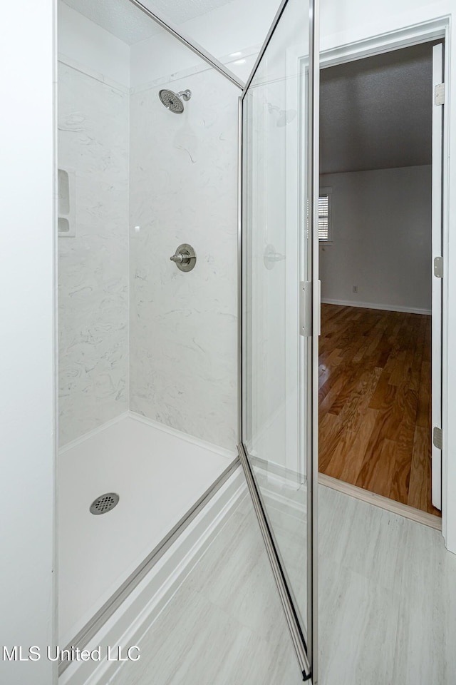 full bathroom with a shower stall and wood finished floors