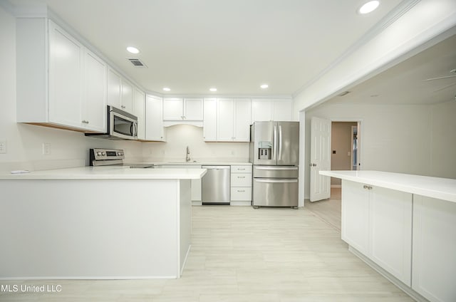 kitchen featuring stainless steel appliances, light countertops, visible vents, white cabinets, and a sink