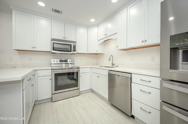 kitchen featuring stainless steel appliances, light countertops, a sink, and visible vents