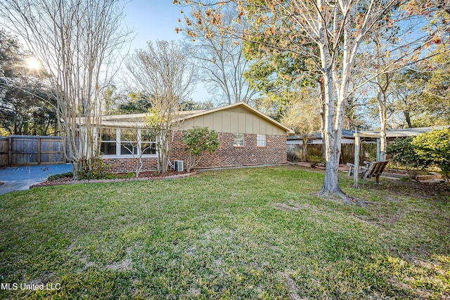 exterior space featuring brick siding, board and batten siding, a front yard, and fence