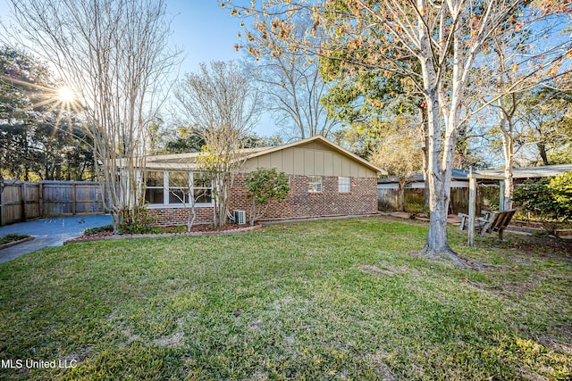 exterior space with a yard, a fenced backyard, board and batten siding, and brick siding