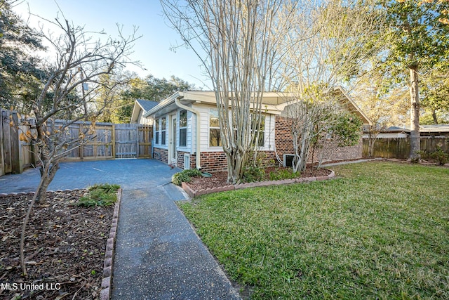 view of home's exterior with fence, a lawn, and brick siding