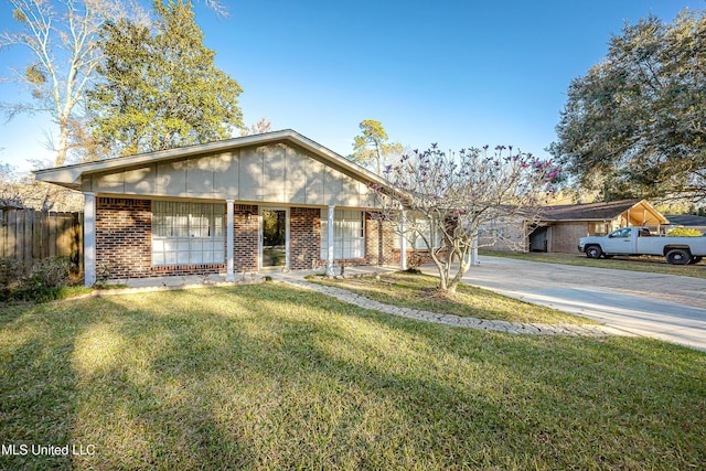 single story home with concrete driveway, brick siding, a front yard, and fence