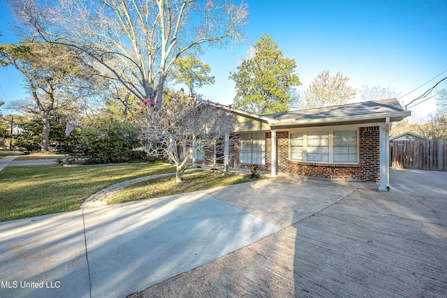 ranch-style house featuring brick siding, fence, and a front lawn