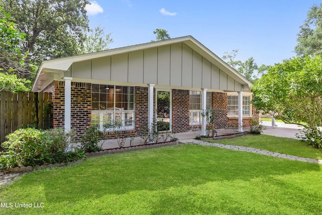 view of front of house with fence, a front lawn, board and batten siding, and brick siding