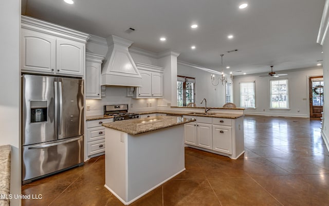 kitchen featuring appliances with stainless steel finishes, a center island, decorative light fixtures, sink, and kitchen peninsula