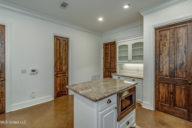 kitchen featuring white cabinets, tile patterned floors, and stainless steel microwave