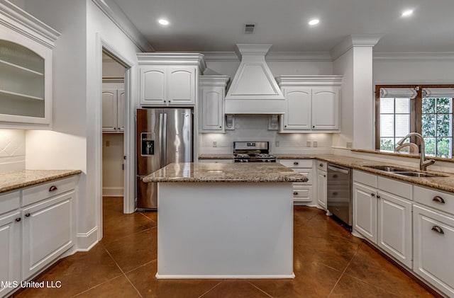 kitchen with premium range hood, appliances with stainless steel finishes, white cabinetry, and sink