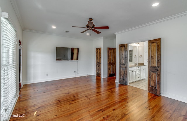 unfurnished living room featuring light hardwood / wood-style floors, sink, crown molding, and ceiling fan