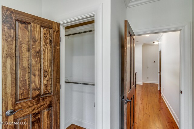 hall with ornamental molding and light hardwood / wood-style floors