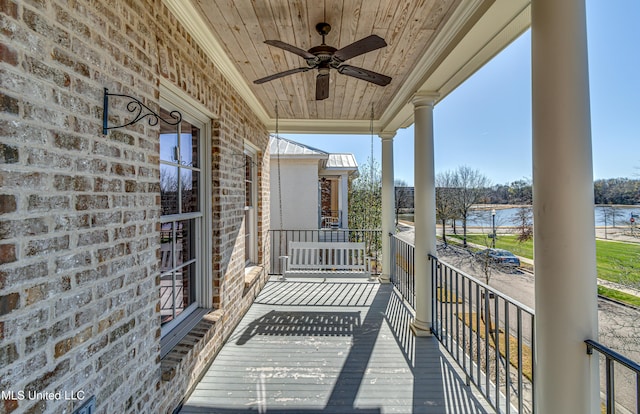 balcony with ceiling fan, a water view, and covered porch