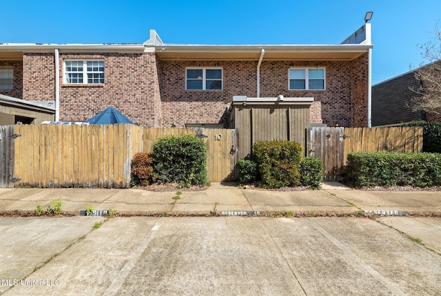view of front of home with brick siding, a gate, and a fenced front yard