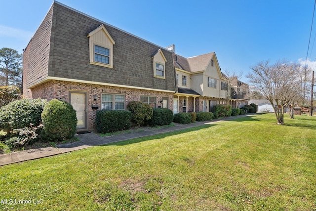 view of front of home featuring brick siding, a front yard, and roof with shingles