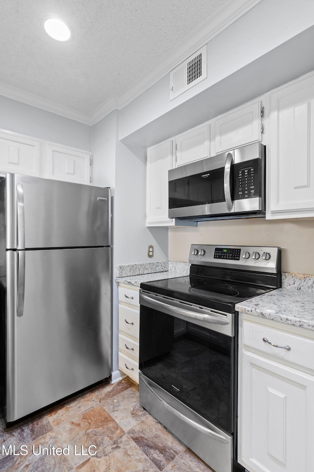 kitchen featuring visible vents, white cabinets, ornamental molding, and stainless steel appliances