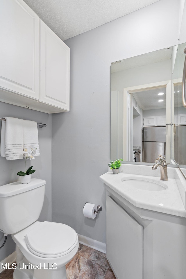bathroom with baseboards, a textured ceiling, toilet, and vanity