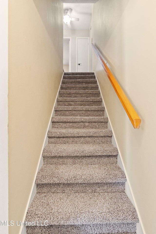 stairs featuring baseboards and ceiling fan