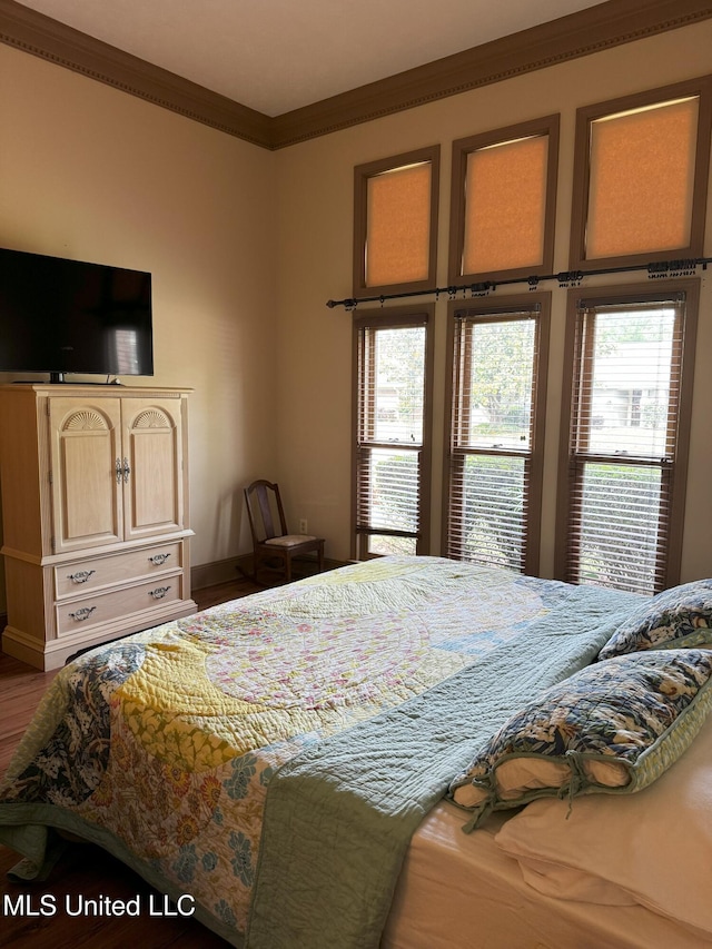 bedroom featuring crown molding, multiple windows, and wood finished floors