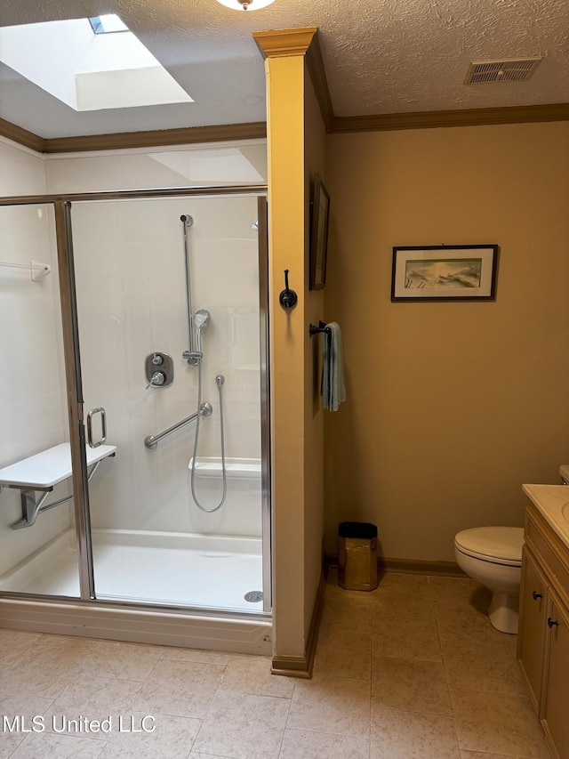 bathroom with vanity, toilet, a shower stall, a skylight, and visible vents