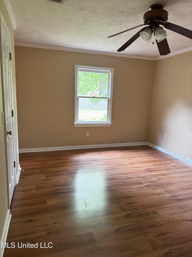 empty room with a textured ceiling, a ceiling fan, baseboards, wood finished floors, and ornamental molding