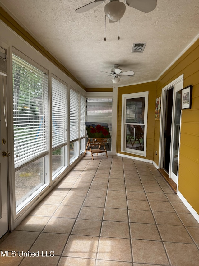 unfurnished sunroom with a textured ceiling, visible vents, ornamental molding, and tile patterned flooring