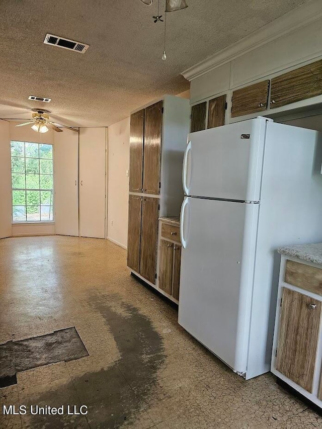 kitchen with white fridge, ceiling fan, and a textured ceiling