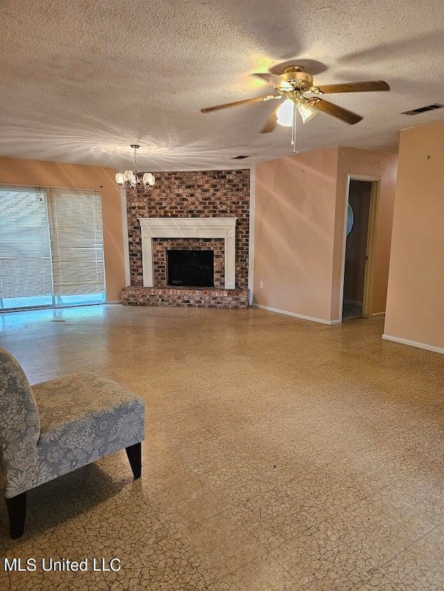 living room featuring ceiling fan with notable chandelier, a textured ceiling, and a fireplace