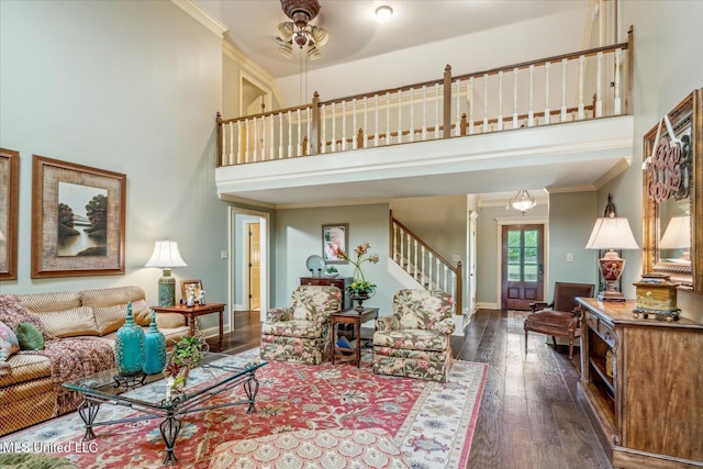 living area featuring stairway, crown molding, a high ceiling, and dark wood-type flooring