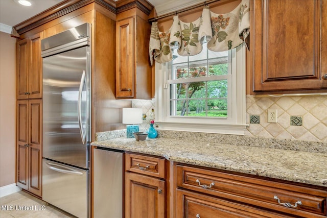 kitchen featuring stainless steel built in fridge, light stone counters, crown molding, and brown cabinets