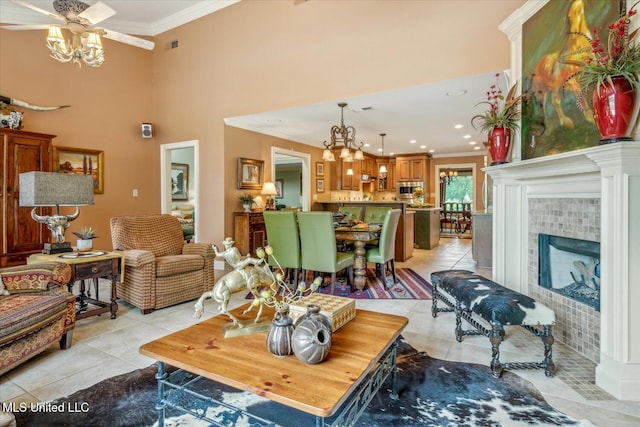 living area with a tiled fireplace, a high ceiling, light tile patterned floors, a notable chandelier, and ornamental molding