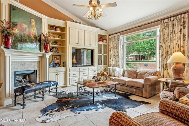 living area with a ceiling fan, crown molding, vaulted ceiling, a tile fireplace, and light tile patterned floors
