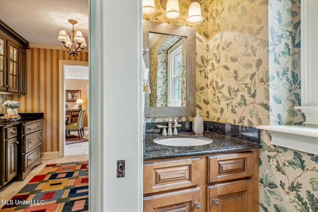 bathroom with crown molding, tile patterned flooring, vanity, a notable chandelier, and wallpapered walls