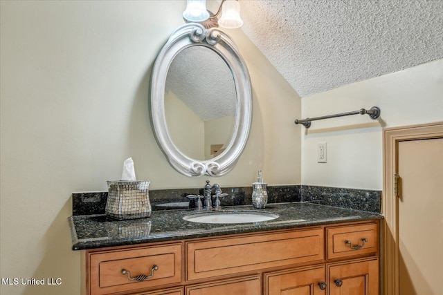 bathroom with a textured ceiling, vaulted ceiling, and vanity