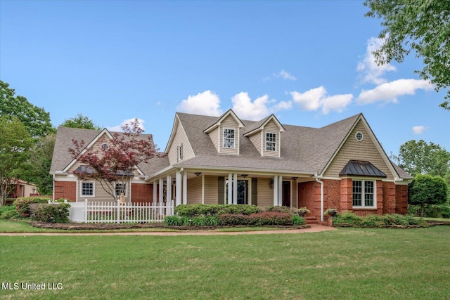 view of front of property featuring roof with shingles, covered porch, a front yard, and brick siding