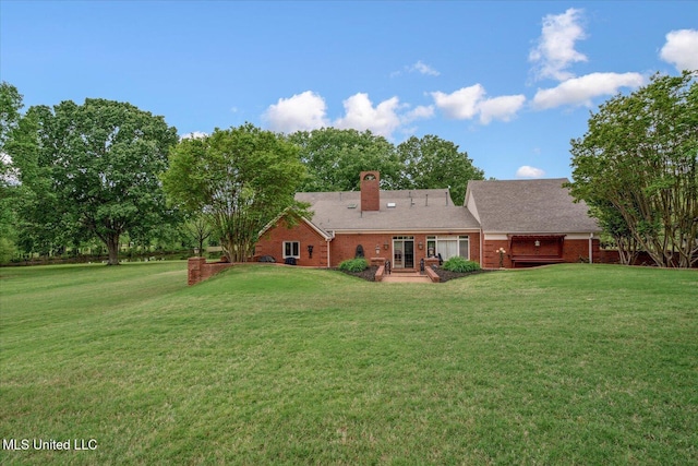 back of property with a lawn, a chimney, and brick siding
