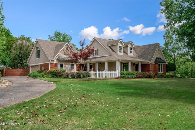 view of front of house featuring an attached garage, aphalt driveway, a front yard, brick siding, and a porch