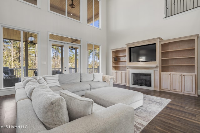 living room with a towering ceiling, a wealth of natural light, dark wood-type flooring, and wood ceiling