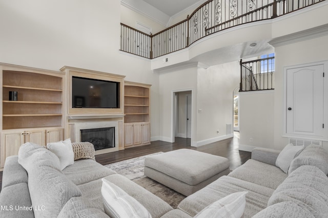 living room featuring dark hardwood / wood-style flooring, a towering ceiling, and ornamental molding