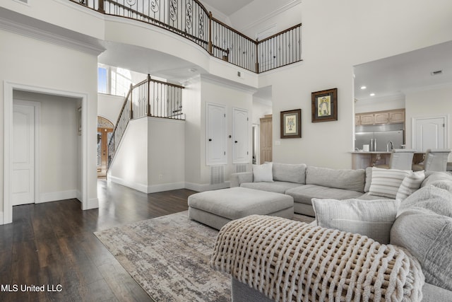 living room with a high ceiling, dark hardwood / wood-style floors, and ornamental molding