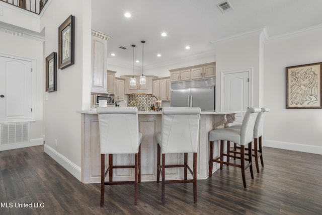 kitchen featuring kitchen peninsula, a kitchen breakfast bar, tasteful backsplash, built in appliances, and decorative light fixtures