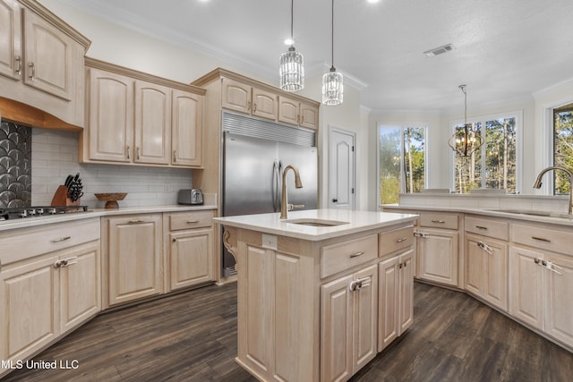 kitchen with sink, hanging light fixtures, an island with sink, decorative backsplash, and light brown cabinetry