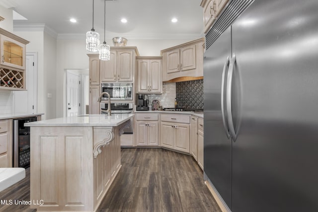 kitchen featuring backsplash, light brown cabinets, built in appliances, pendant lighting, and an island with sink