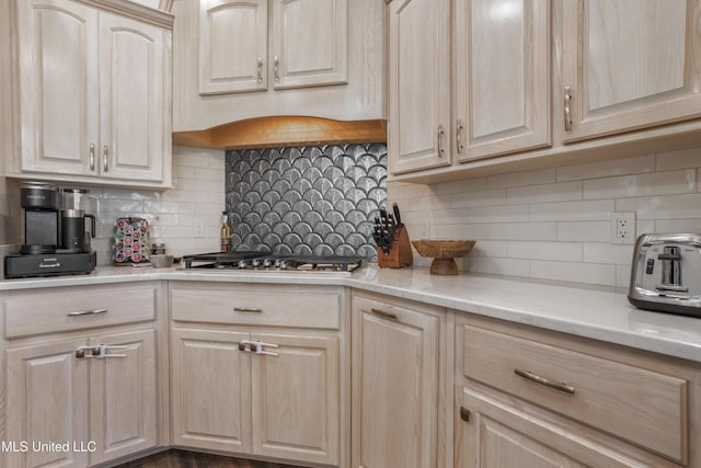 kitchen featuring stainless steel gas stovetop, decorative backsplash, and light brown cabinets