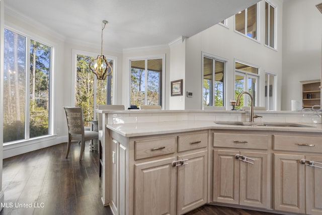 kitchen with dark wood-type flooring, sink, light brown cabinets, pendant lighting, and an inviting chandelier