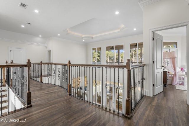 hallway featuring dark hardwood / wood-style flooring, a tray ceiling, and crown molding